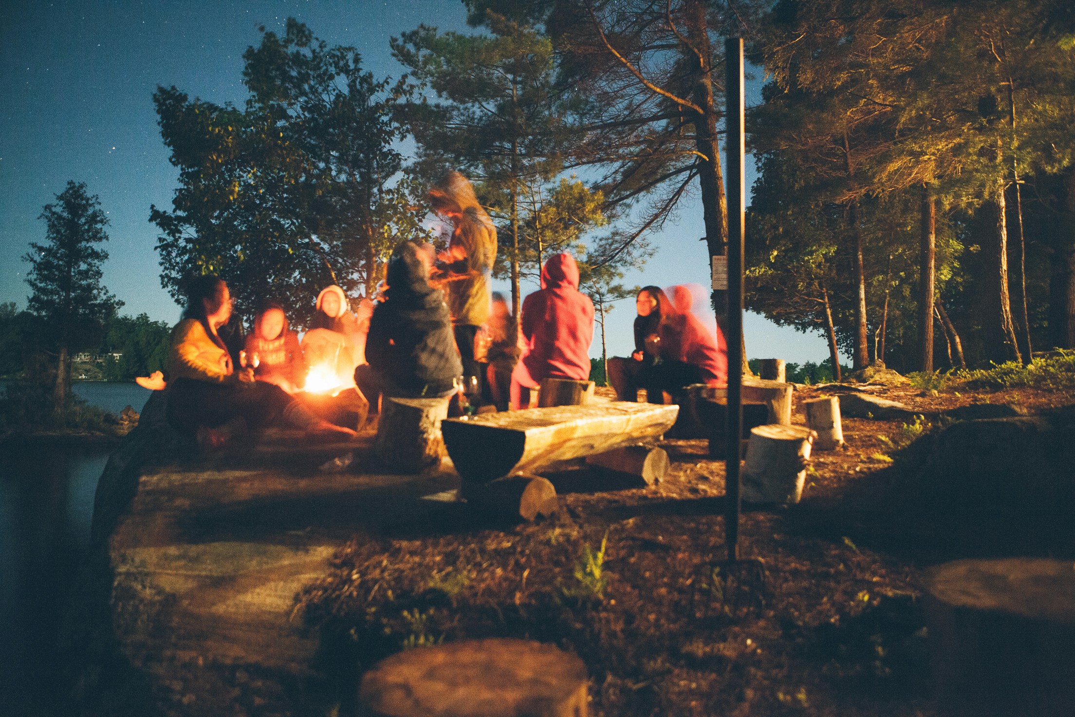 Friends gathered around a fire at their seasonal campsite